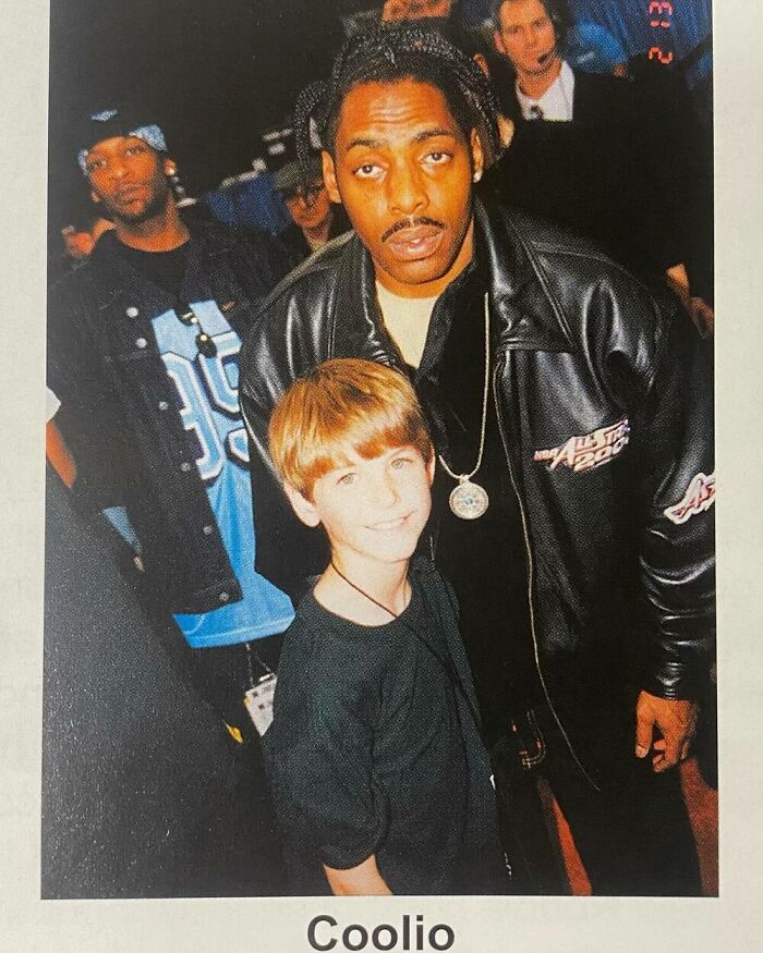 Child posing with celebrity in a crowd, wearing casual attire, capturing a moment with a famous figure.