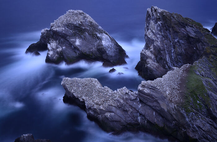 Majestic rocks surrounded by ocean, covered in nesting birds, captured by Jose Manuel Grandío.