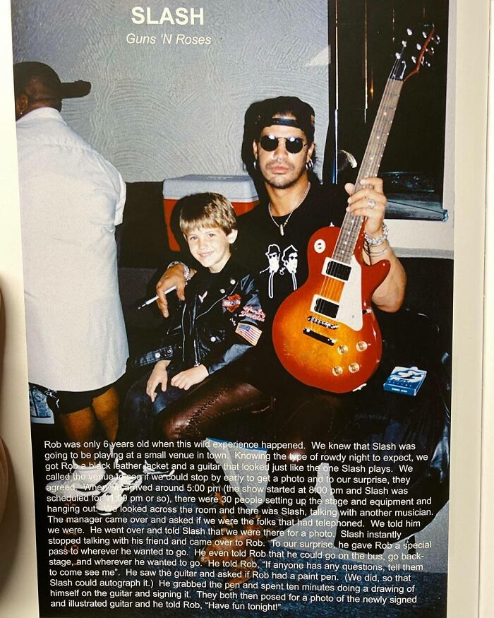 Child posing with celebrity musician holding a guitar, both smiling for the camera.