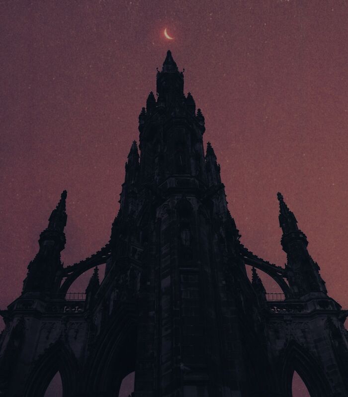 Gothic tower silhouetted against a starry sky and crescent moon, showcasing dark escapism photography.