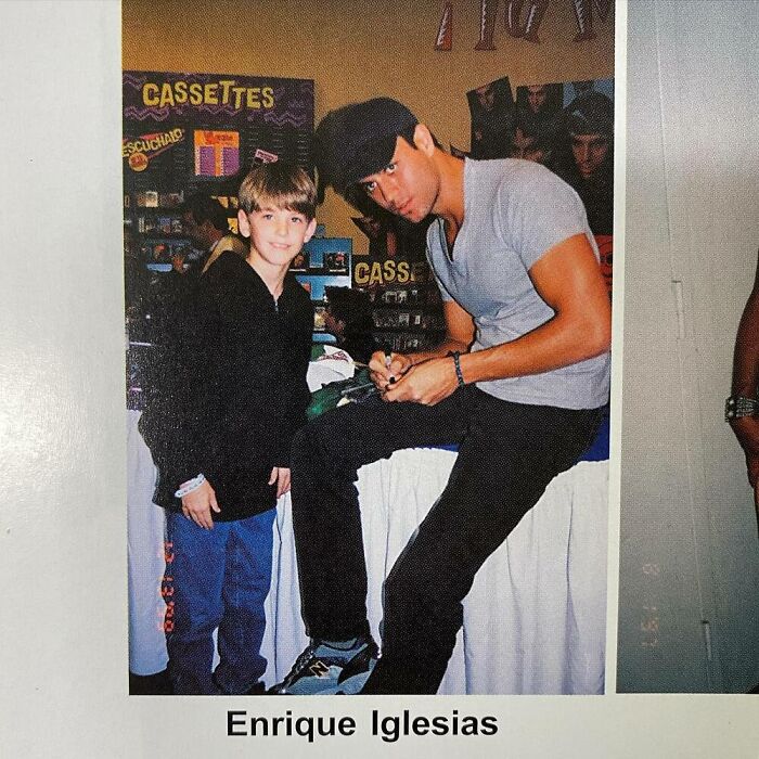 Young boy meeting a celebrity at an event, with CDs in the background.