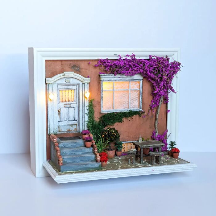 Miniature scene by Tamar Cohen featuring a cozy patio with vibrant flowers, a table, and a classic white door.