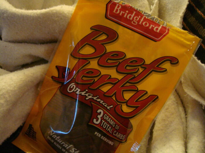 Package of Bridgford beef jerky, a popular restaurant food item, displayed on a soft textured background.