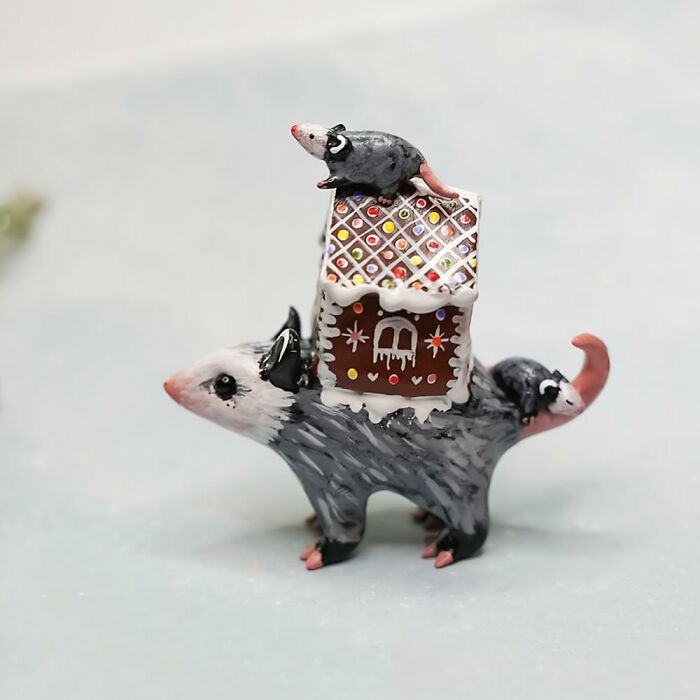 Pocket-sized animal figurine by Vallavica, featuring a possum with a gingerbread house and tiny mice on its back.