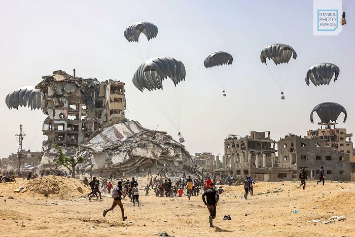 Paratroopers descend over war-torn city, capturing a powerful moment at the Istanbul Photo Awards 2025.