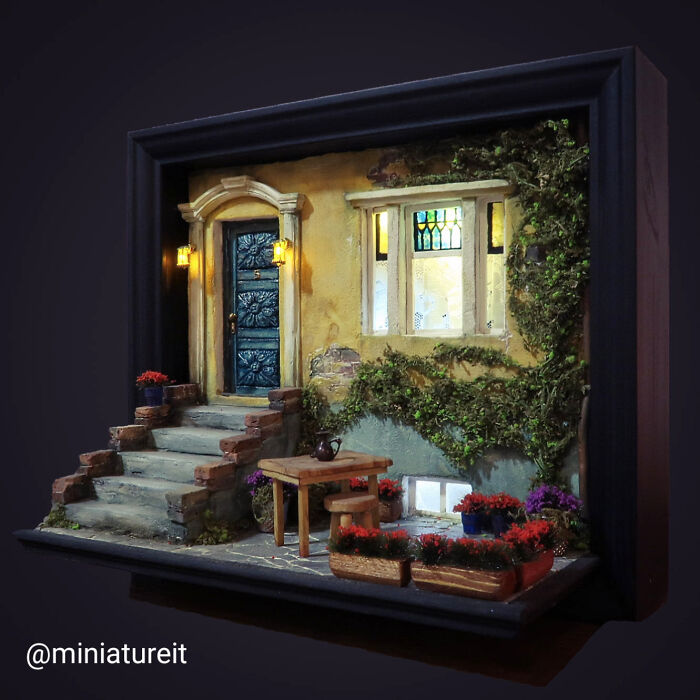 Miniature scene by Tamar Cohen featuring a detailed house facade with steps, plants, and a table, evoking tiny worlds.