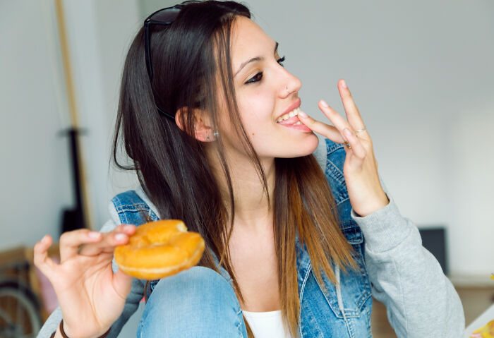 Woman enjoying a donut, wearing a denim jacket, highlighting relationship insights from a new girlfriend perspective.