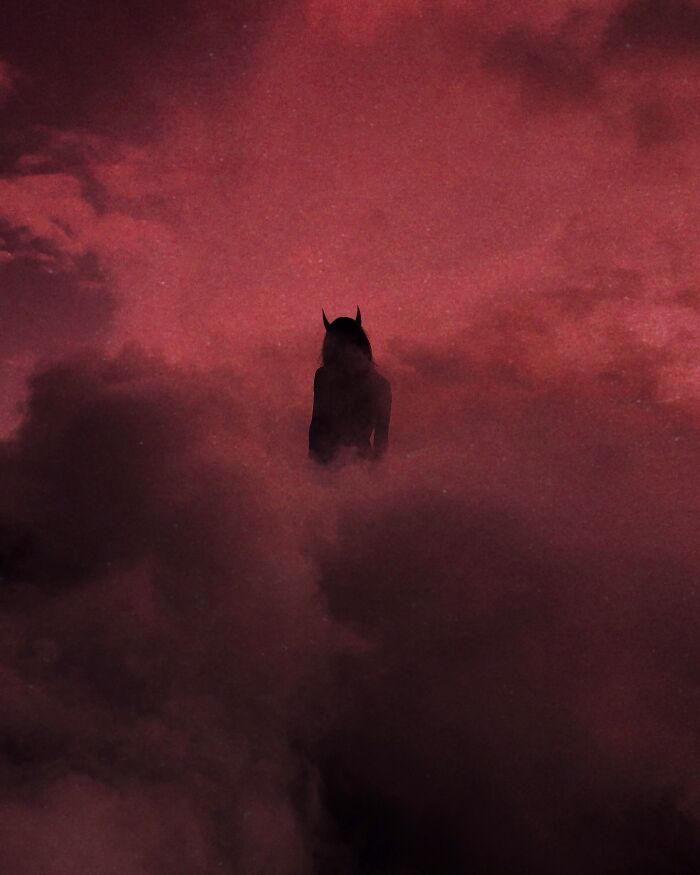 Dark escapism photography; silhouette of a figure with horned headpiece surrounded by ominous clouds in a red-hued sky.