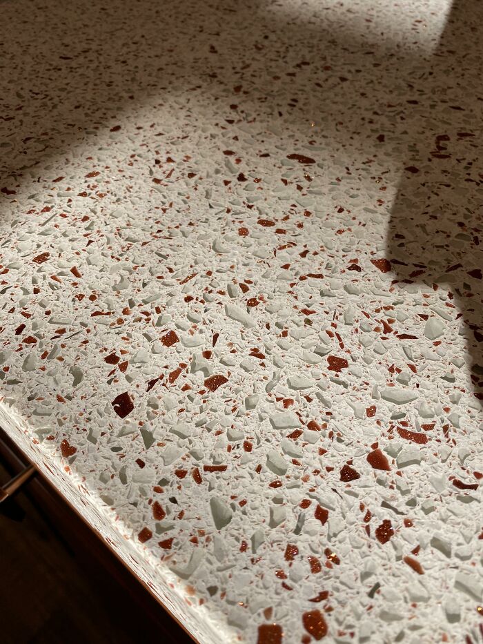 Speckled countertop surface under sunlight, featuring red and white patterns, highlighting impractical home decor.