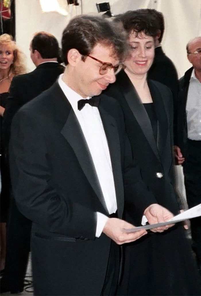 Man in a tuxedo and glasses at an event with woman smiling, highlighting wholesome stars.