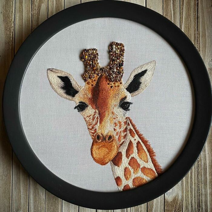 Embroidery work of a giraffe in a circular frame, showcasing detailed and colorful stitching.