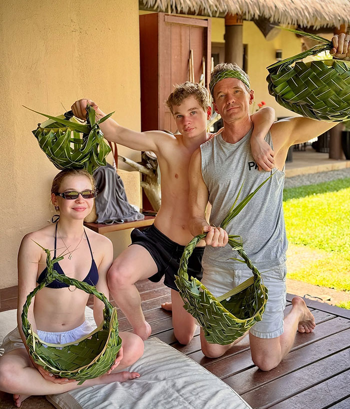 Group posing with woven baskets on a Fiji trip, enjoying a sunny day outdoors.