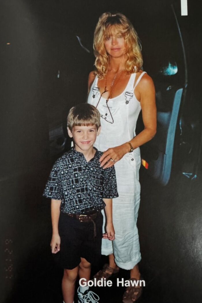 Child posing with a celebrity in casual attire, smiling outdoors.