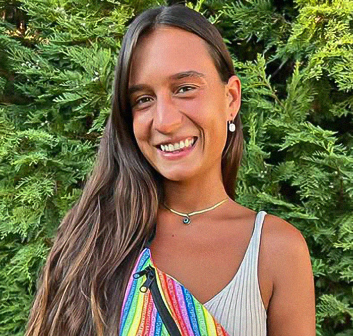 Young woman smiling outdoors, wearing a colorful dress.