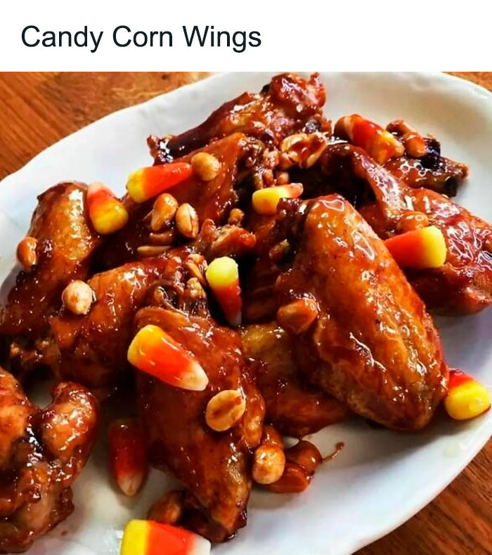 Unappetizing dish of sticky wings with candy corn and peanuts on a white plate.