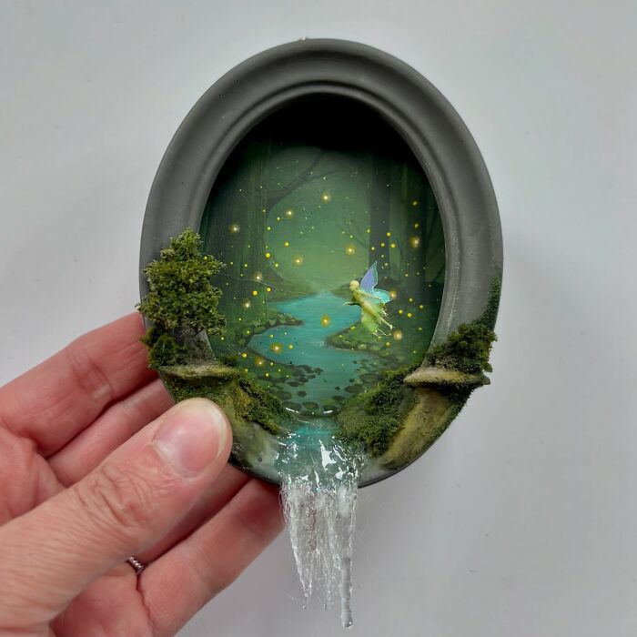 Miniature forest diorama with fairy, glowing lights, and waterfall, held in hand. Perfect for alien and mystery aficionados.