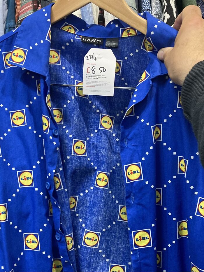 Blue shirt with repeating Lidl logo pattern, priced at £8.50, found in secondhand shop, held by a person.