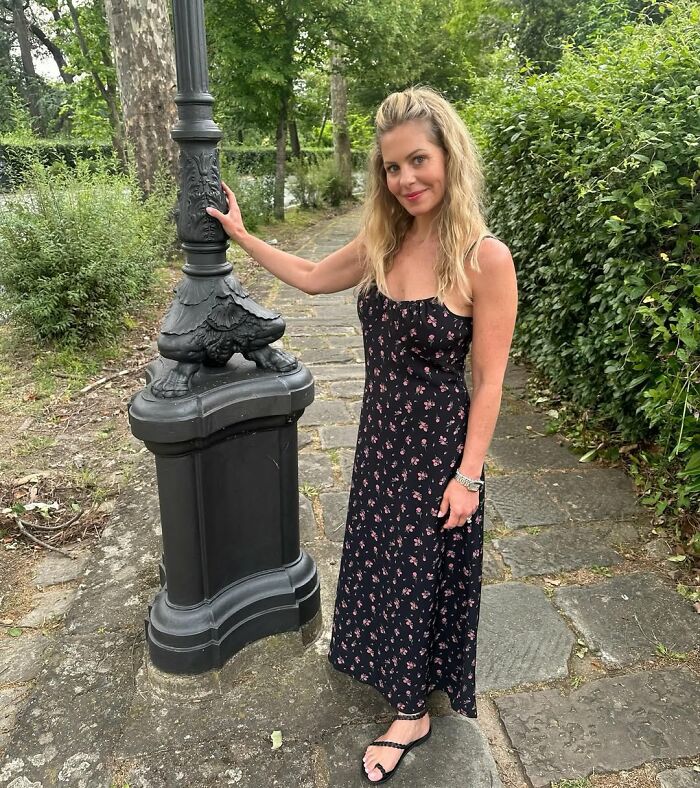 Woman in a floral dress posing outdoors next to a vintage lamppost, illustrating celebrity encounters that went well or bad.
