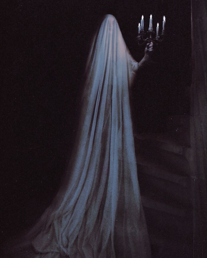 Ghostly figure draped in fabric holding a candelabra, showcasing dark escapism photography.
