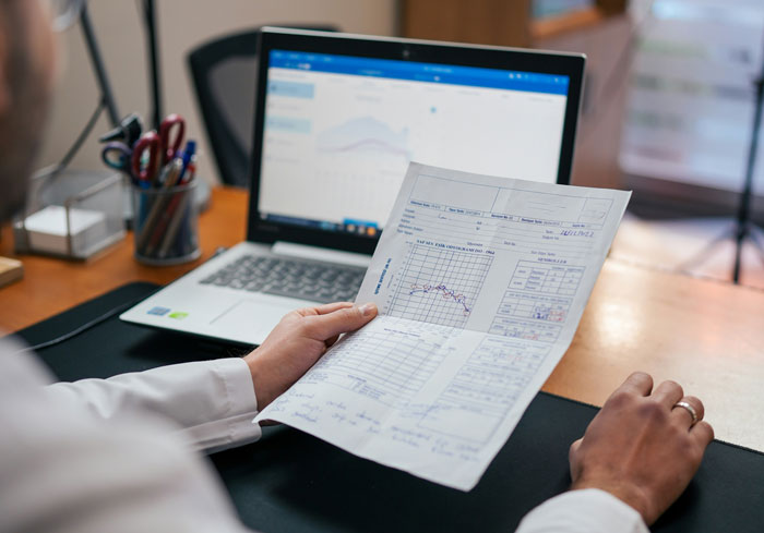 Person reviewing family DNA results, seated at a desk with a laptop in the background.