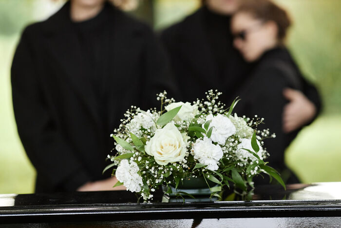Funeral scene with floral arrangement on a casket, evoking unforgettable high school incidents.