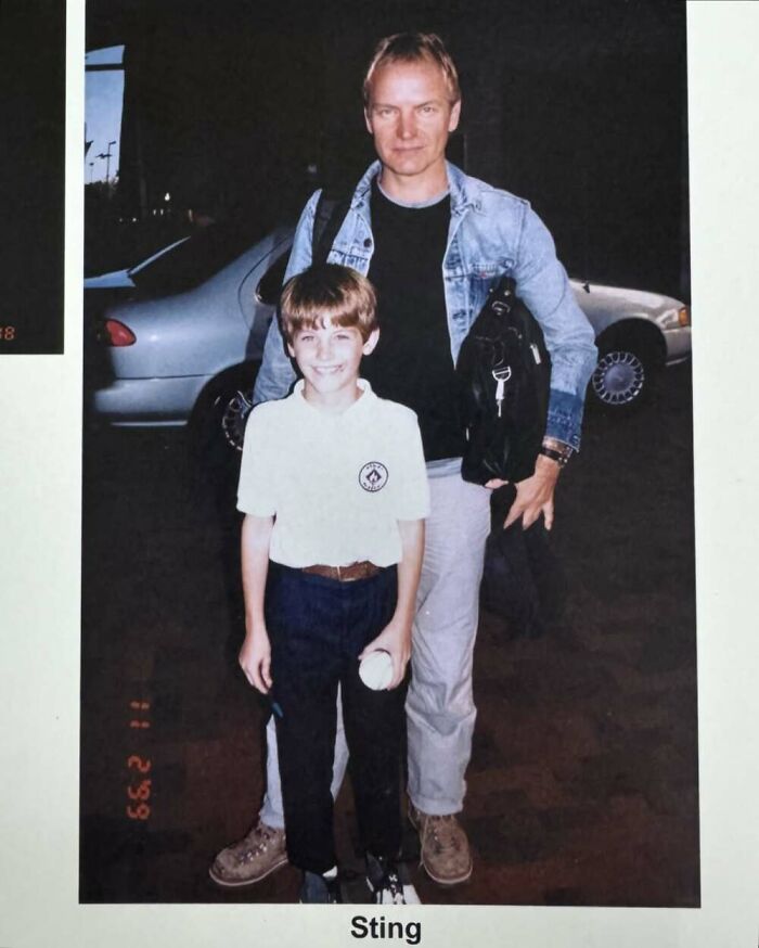 A young fan takes a photo with a celebrity, both smiling, against a car backdrop.