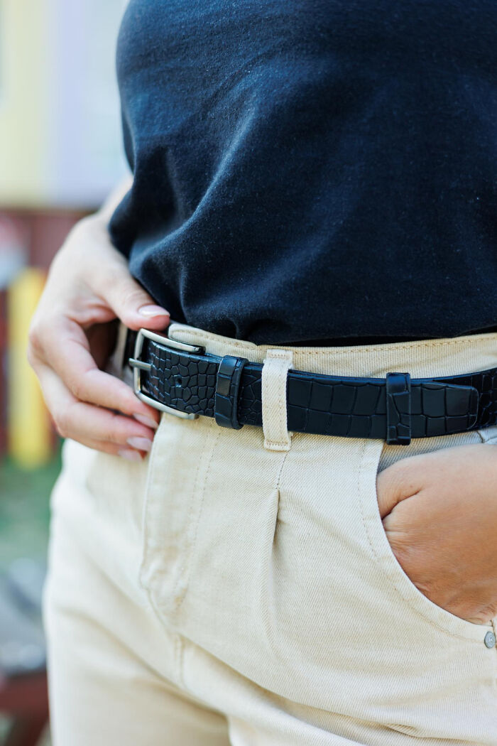 Person in black shirt and beige pants with hands in pockets, showcasing house fashion.