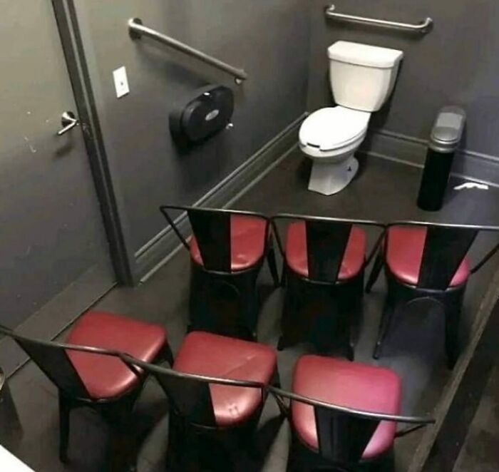 Public bathroom with chairs humorously arranged facing the toilet, creating an absurdly funny scene shared on Instagram.