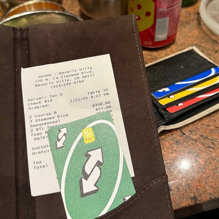 Receipt and wallet with credit cards, featuring a funny card resembling a reverse Uno card.