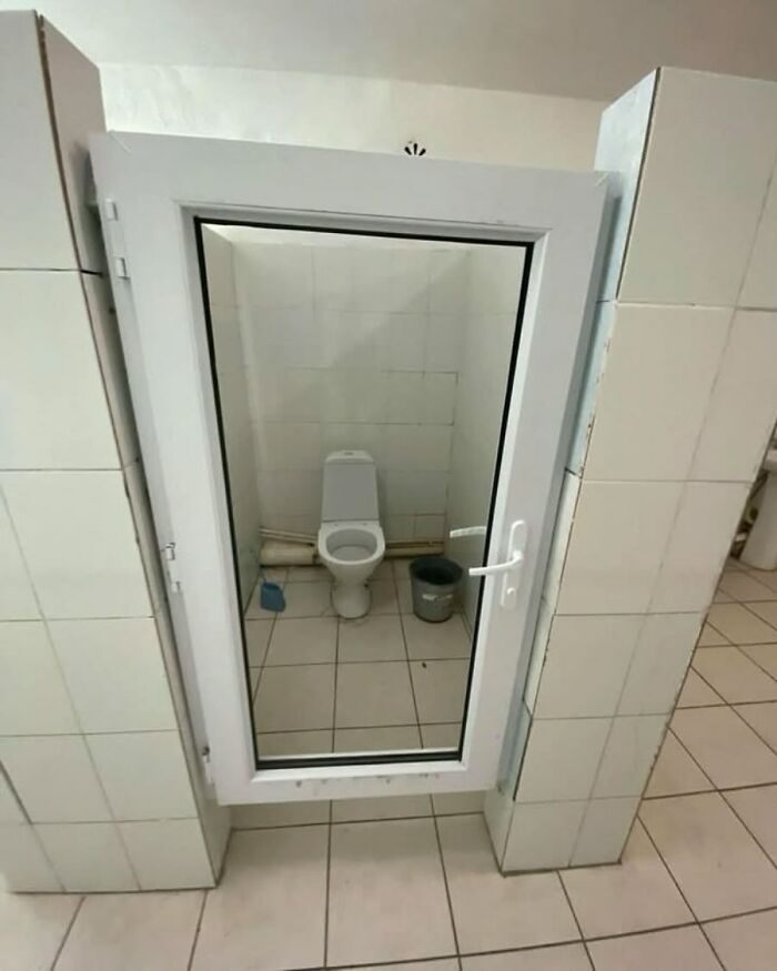 Bathroom with a glass door, showcasing random and humorous design.