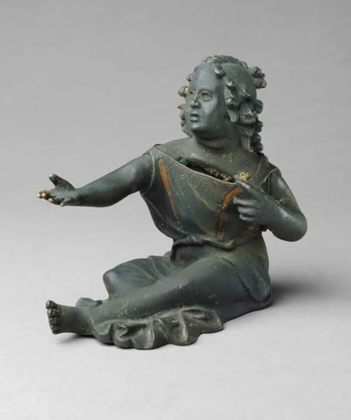 Ancient bronze figurine of a seated person with detailed hair, showcasing craftsmanship in archaeology news and architecture.
