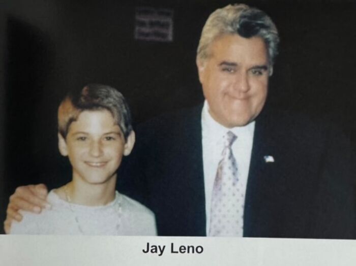 Young boy smiling with a celebrity, both in formal attire, capturing a memorable photo together.
