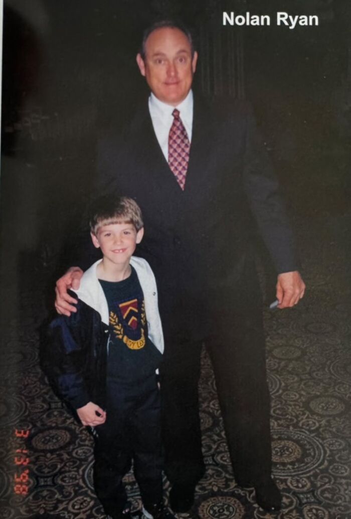 Child posing with a celebrity in formal attire, smiling at the camera.