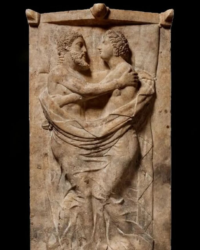 Ancient stone relief sculpture of two embracing figures, showcasing detailed craftsmanship in archaeology and architecture.