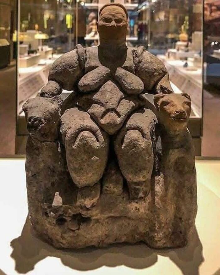 Ancient sculpture of a seated figure with animal figures, displayed in a museum, highlighting archaeology and architecture details.