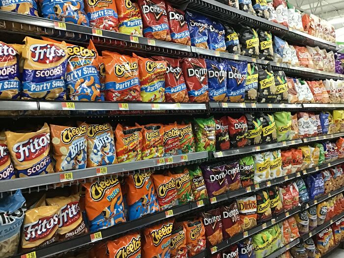 A supermarket aisle filled with various restaurant food snack products like chips from multiple popular brands.