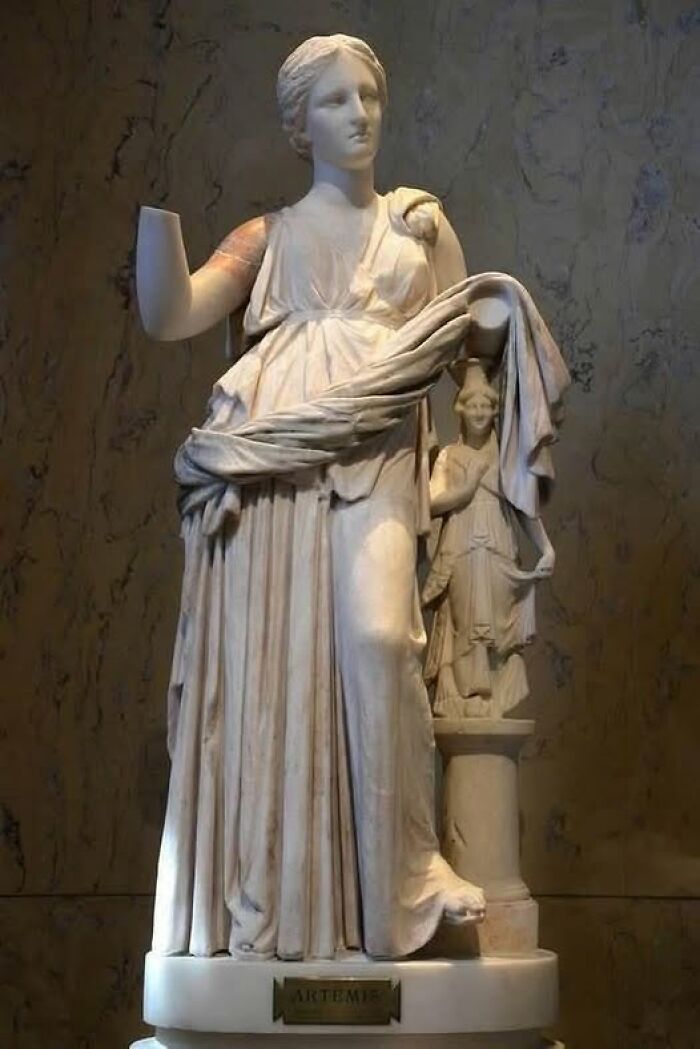 Marble statue of Artemis with intricate drapery and a smaller figure, featured in archaeology news and architecture topics.