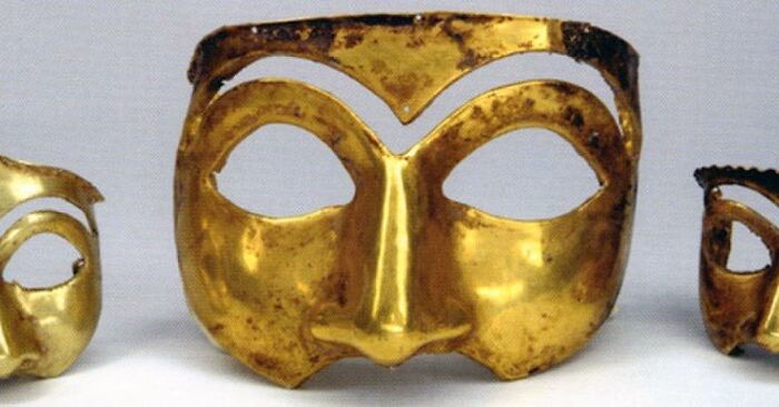Three ancient gold masks displayed against a plain background, highlighting archaeology and historical artifacts.
