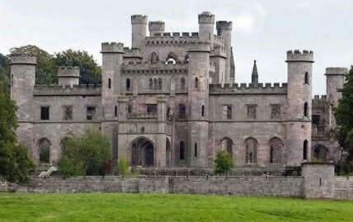 Stone castle with multiple towers and battlements surrounded by greenery, featured in archaeology news and architecture.