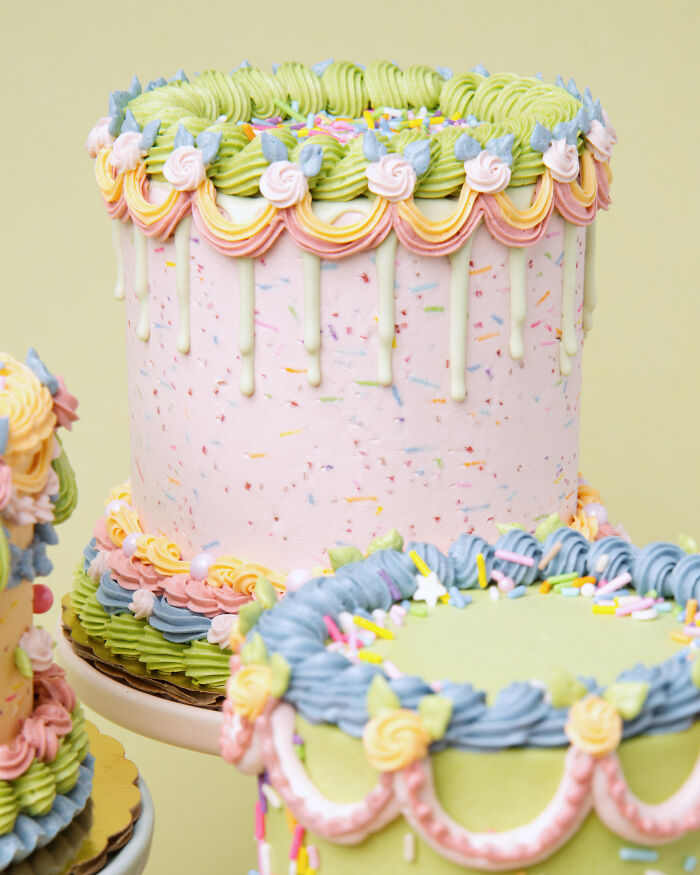Colorful vegan cakes with intricate icing designs against a light green background.