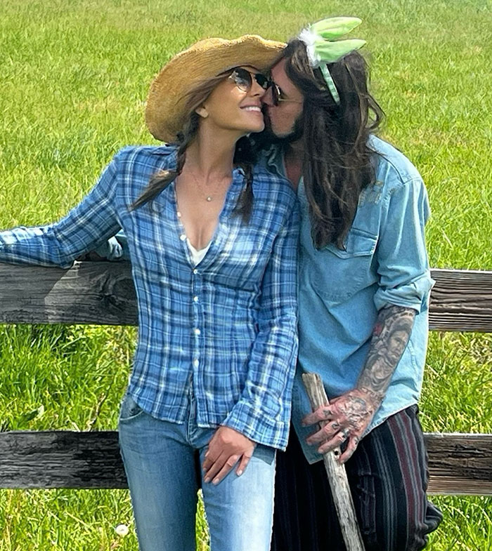 A couple in casual outfits sharing a moment by a fence on Easter, in a grassy field.