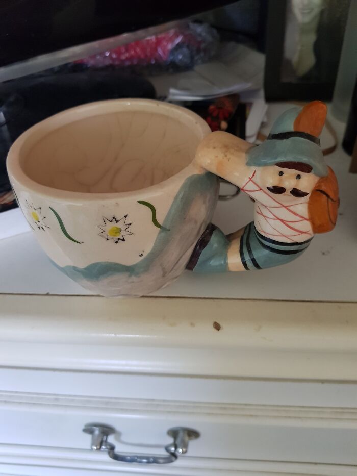 Quirky secondhand treasure: a mug with a hiker handle, discovered in a thrift shop, featuring painted flowers.