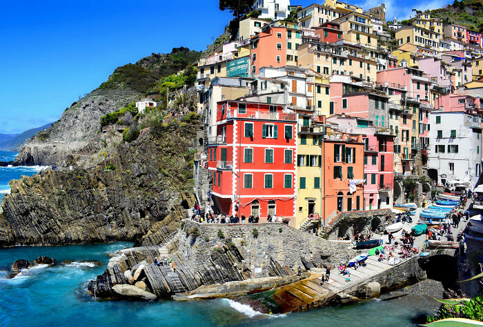 Colorful cliffside city with vibrant buildings resembling a painting.