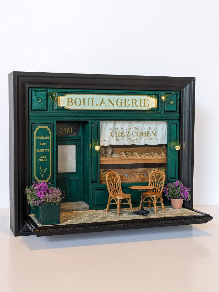 Miniature boulangerie model with green facade and tiny chairs, showcasing the intricate work of Tamar Cohen in tiny worlds.