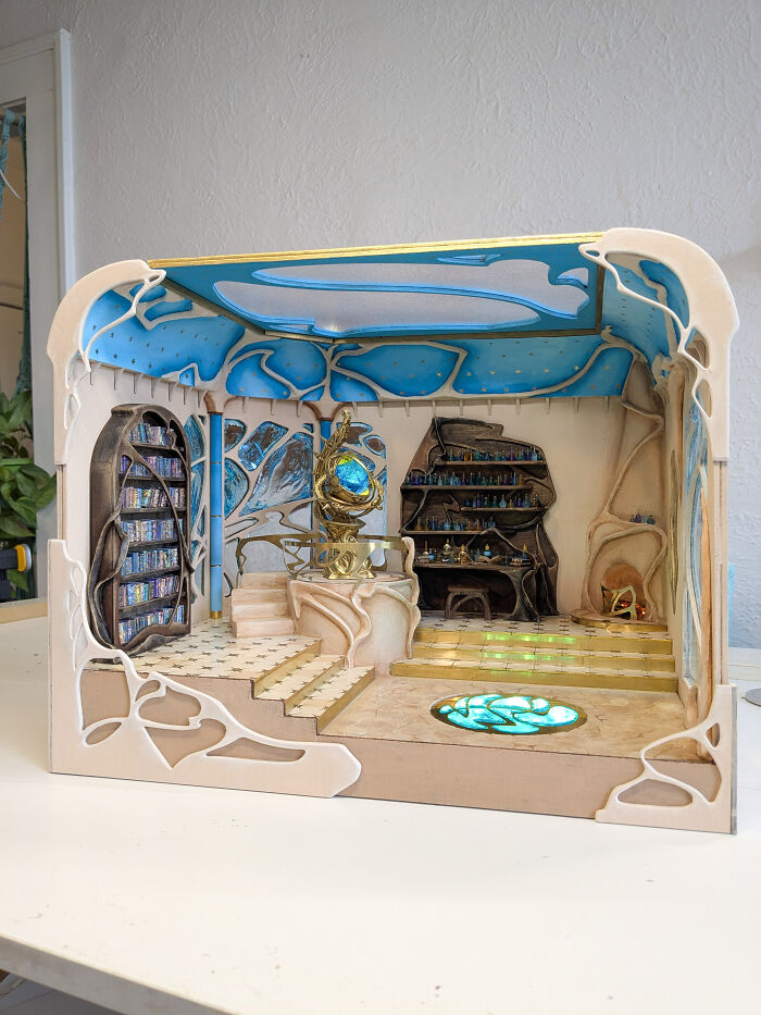 Miniature room design by Tamar Cohen, featuring intricate details, a blue ceiling, and elegant shelves in a tiny world.
