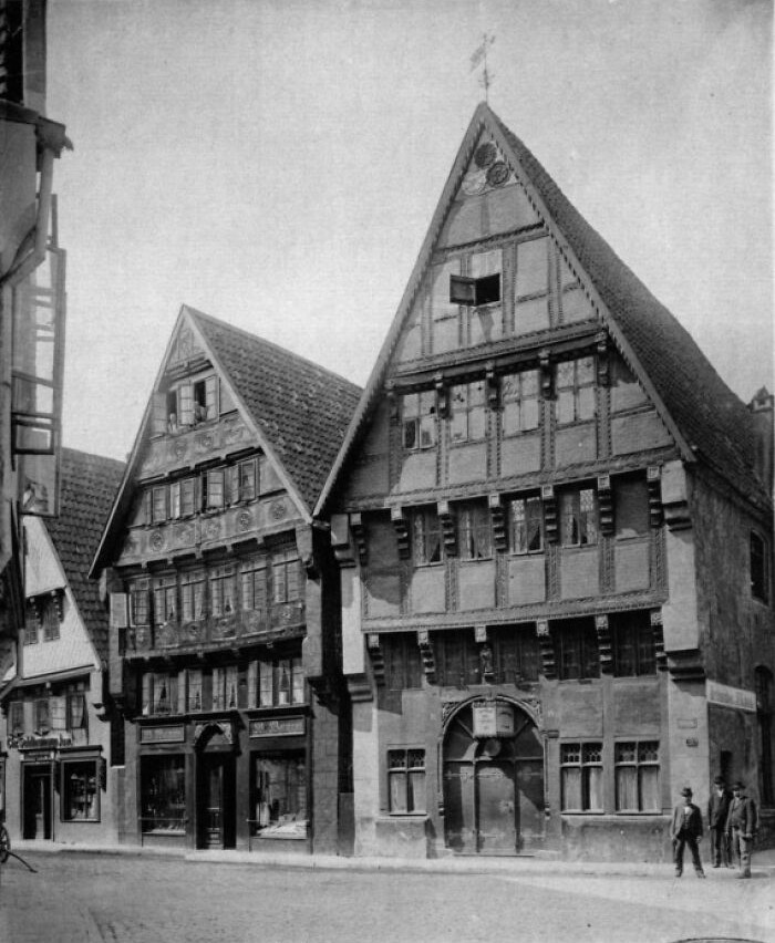 Black and white photo of historic European houses with steep roofs, showing life in Europe 100 years ago on a quiet street.