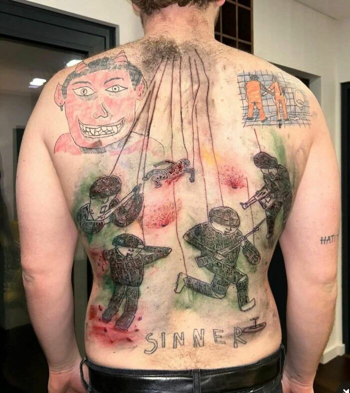 Man with hilariously bad tattoos on his back, featuring devil, stick figures, and "sinner" text.