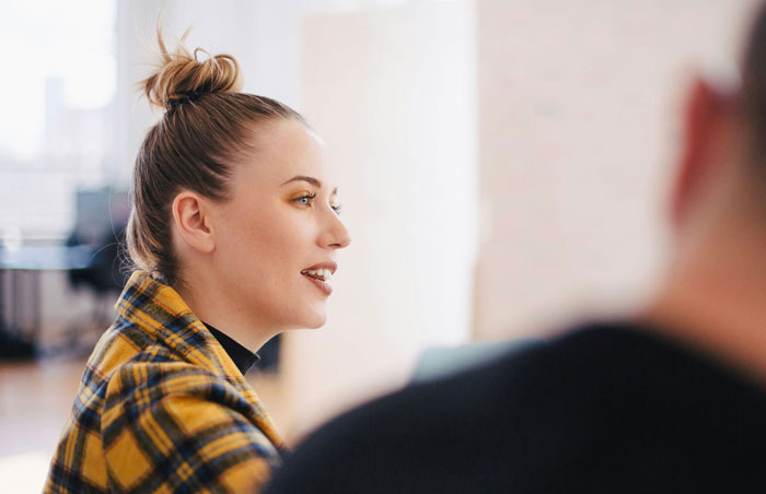 Person in a plaid jacket speaking in a bright office setting, related to job hunting tips.
