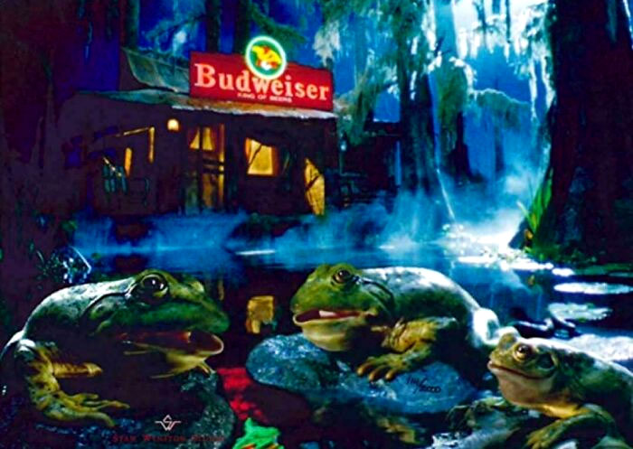 Three frogs in a swamp with a Budweiser sign in the background, evoking nostalgic feelings.
