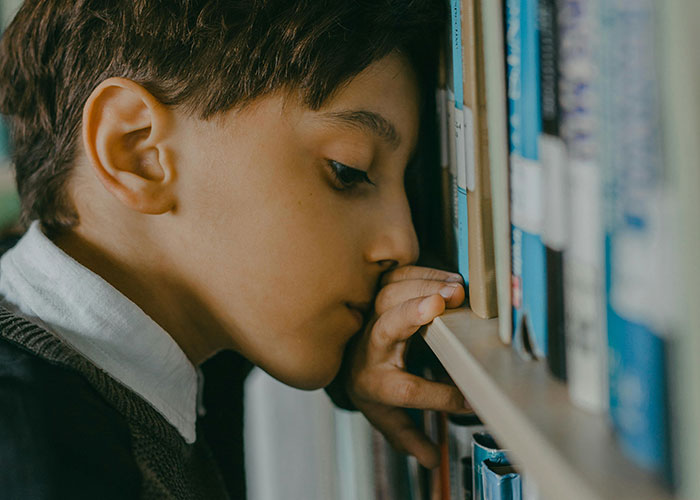 A child looking closely at books on a library shelf, symbolizing curiosity and exploration in education.